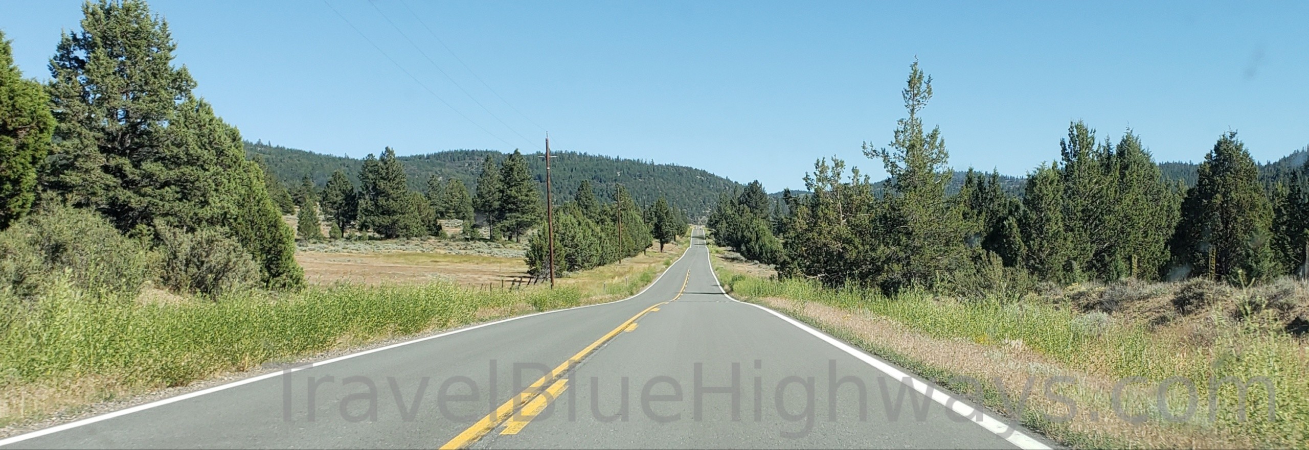 A two lane highway with no traffic on it recedes into the distance